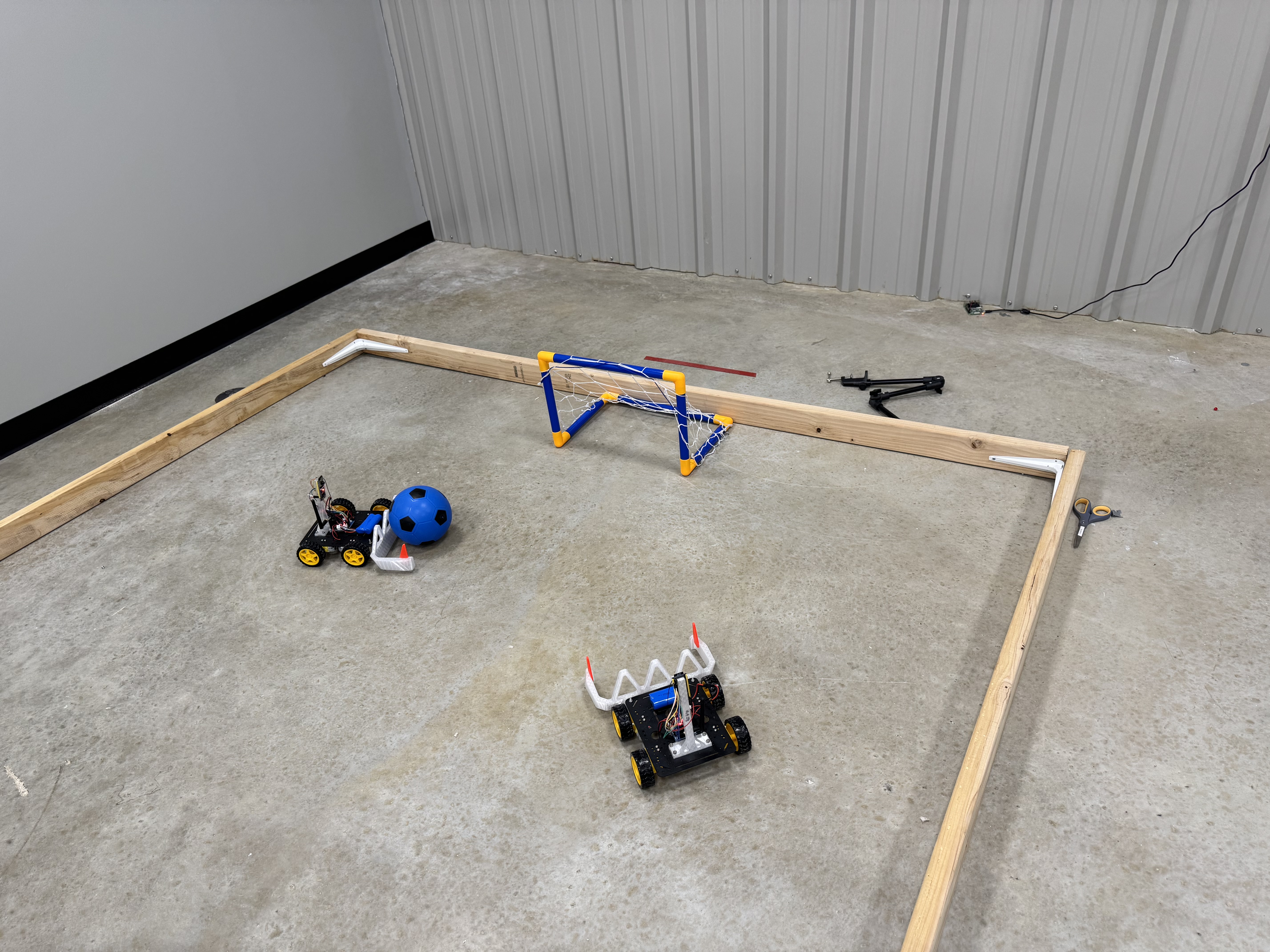 Two soccer robots with a blue ball and goal in the indoor arena